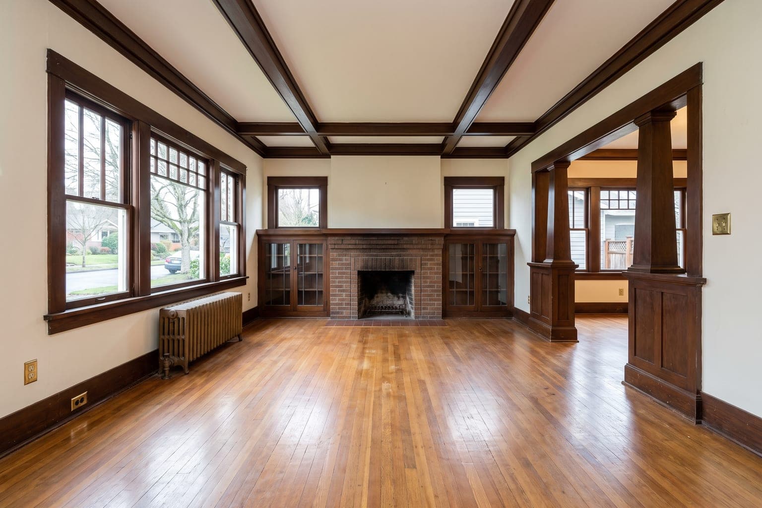 Empty 1920s Craftsman living room before virtual staging - fir floors, brick fireplace with built-ins, boxed-beam ceiling
