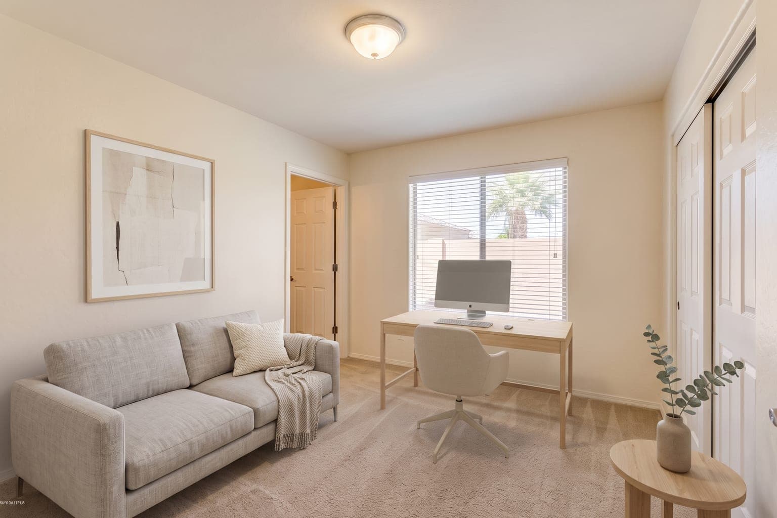 Spare bedroom virtually staged with AI as a home office - light-wood desk, task chair, small sofa and a plant