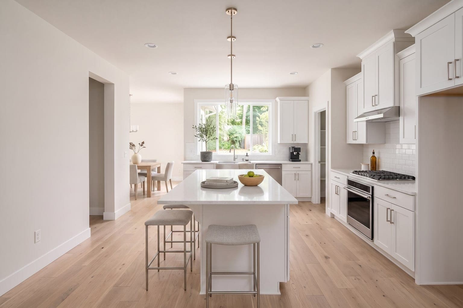 Kitchen virtually staged with AI - bar stools at the island, fruit bowl, greenery and counter decor, cabinets unchanged