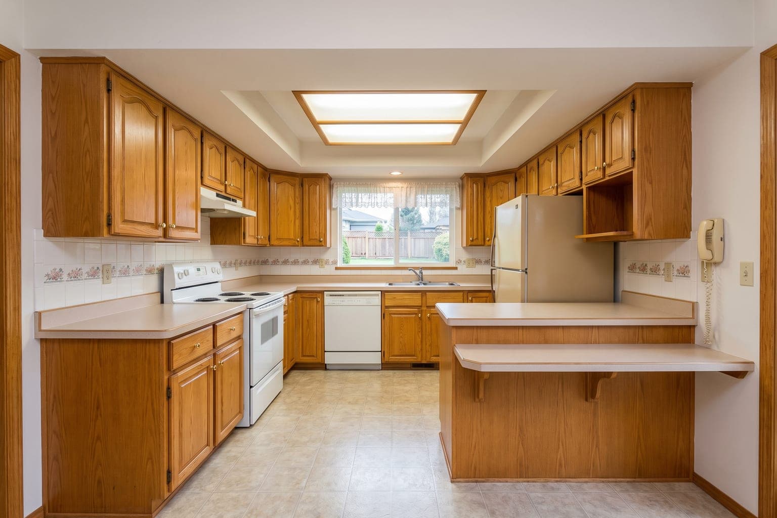 Dated 1990s kitchen before AI renovation - honey-oak cabinets, laminate counters, vinyl floor