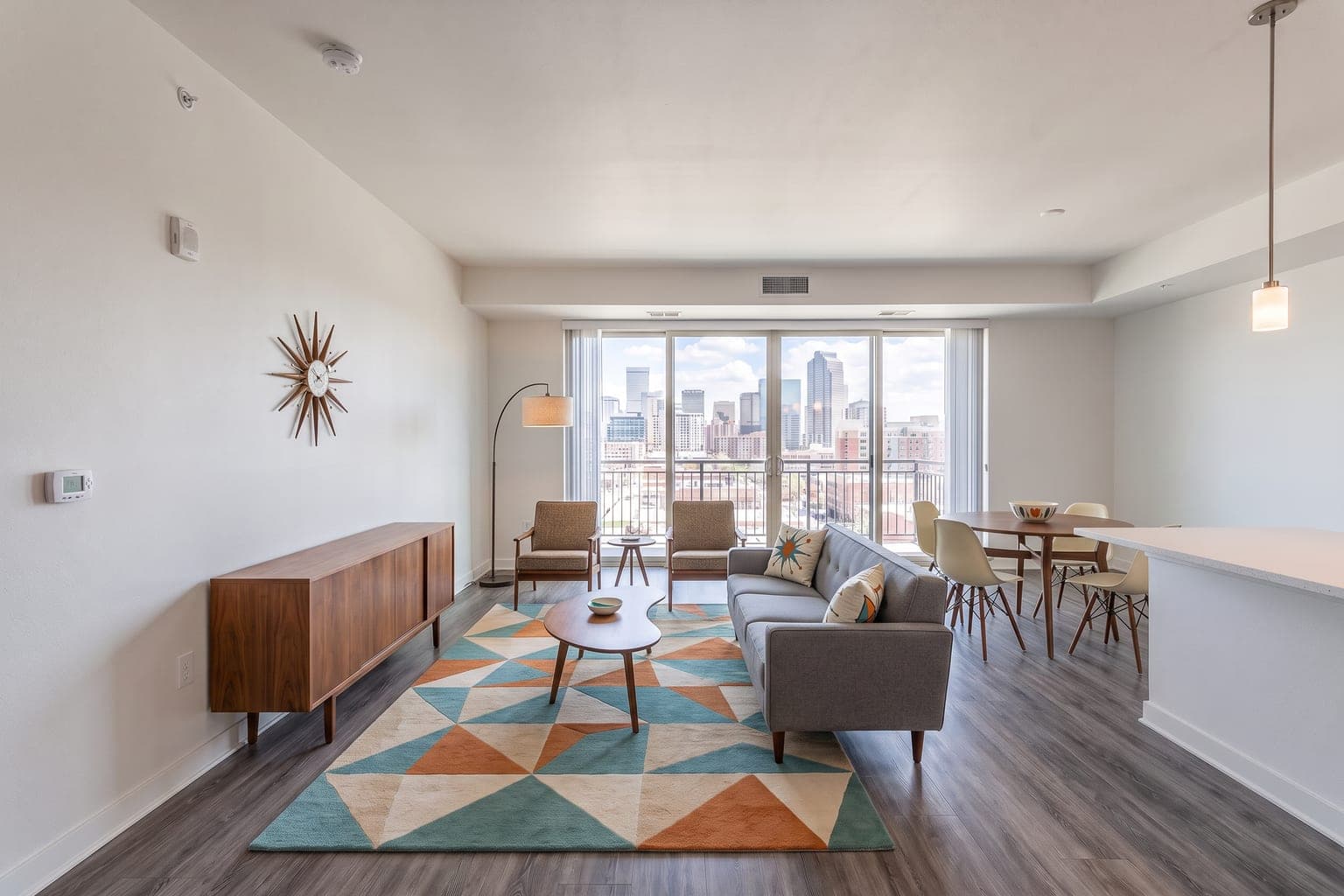 Open-plan condo virtually staged with AI in mid-century modern style - sofa and credenza zone, dining set by the kitchen peninsula