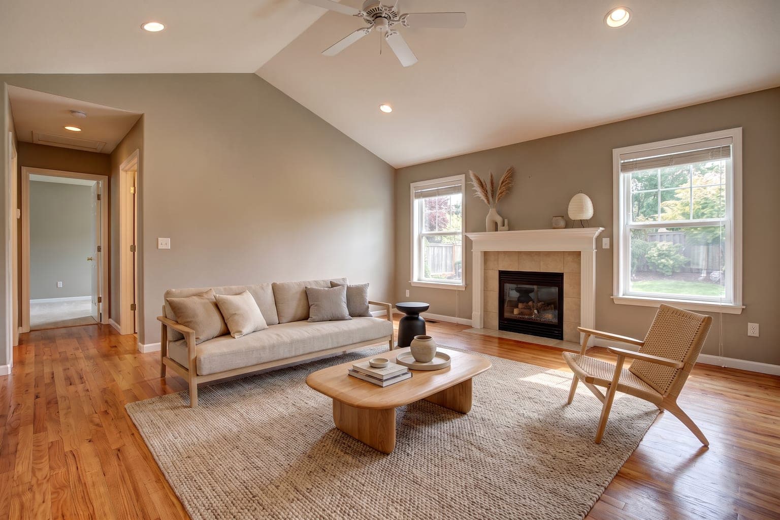 Living room virtually staged with AI in Japandi style - linen sofa, oak coffee table, woven rug and a styled mantel