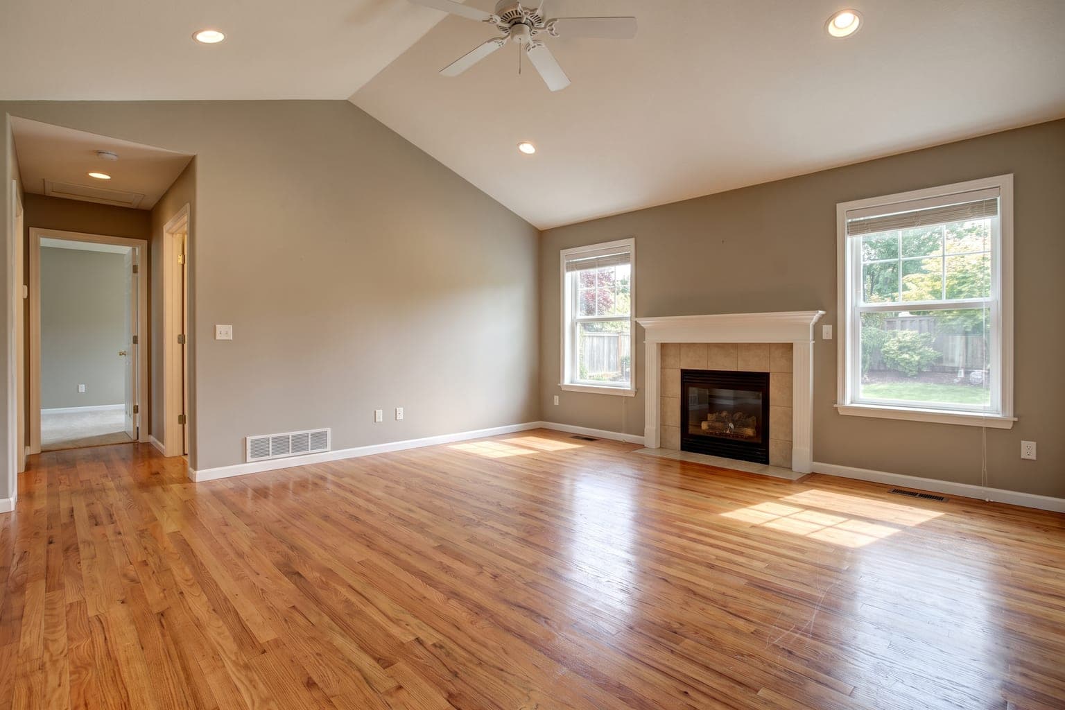 Empty suburban living room before virtual staging - oak hardwood floors, gas fireplace, bare greige walls