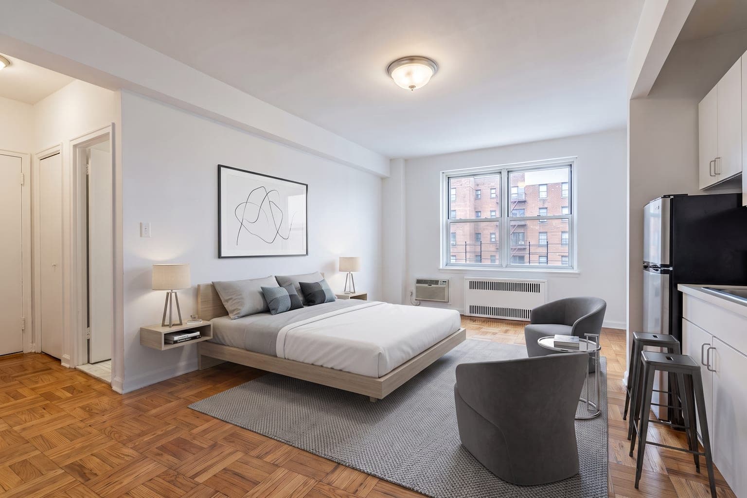 Studio apartment virtually staged with AI in minimalist style - low platform bed, gray armchair, TV stand, rug and a stool at the kitchenette